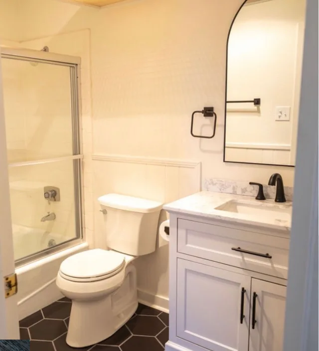 Finished bathroom with a white vanity, dark floor tile, mirror, and shower enclosure