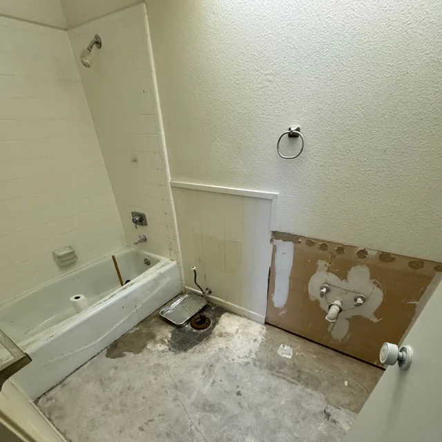 Bathroom before updates, with the vanity removed and floor exposed