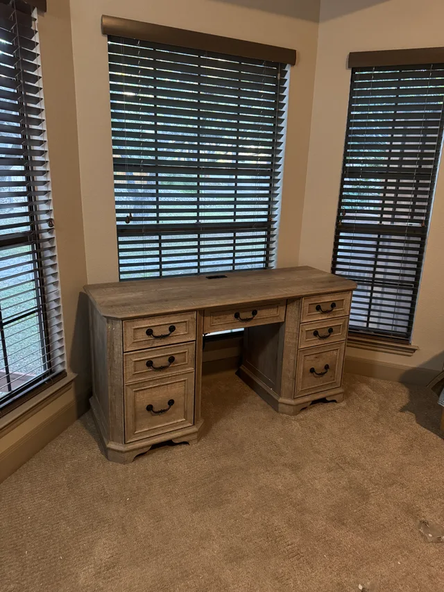 Wooden desk in a room with fitted window blinds