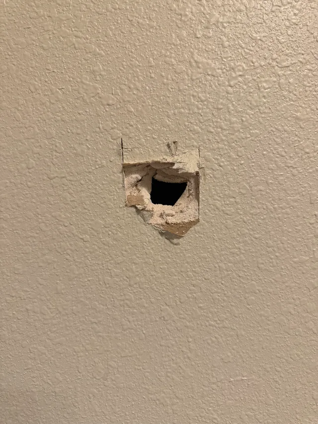 Hole in a textured interior wall before drywall repair