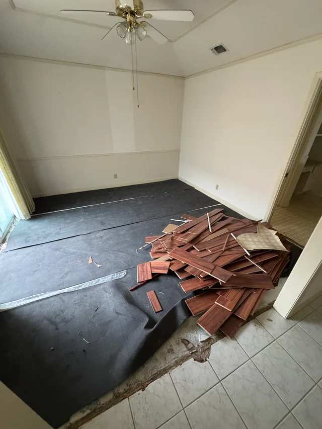 Room with flooring removed and old planks stacked for removal
