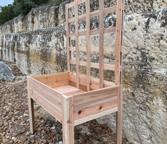 Wooden raised planter with a trellis beside a stone wall