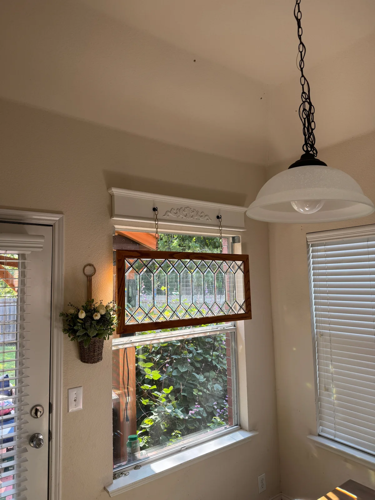 Completed stained-glass panel installation hanging in front of a dining-room window